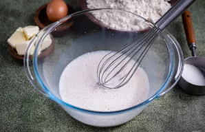 Užpilkite šiltu pienu ir šluotele aktyviai maišykite, kol viskas visiškai ištirps.