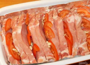 Įdarykite kas antrą įpjovą pomidorais ir česnaku.