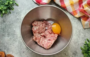 Į dubenį sudėkite maltą mėsą (pvz., kiaulienos ir jautienos mišinį) ir įmuškite kiaušinį.