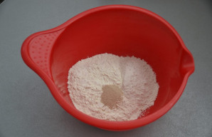 Į tešlos maišymo indą suberkite visus miltus ir sausas mieles, išmaišykite.