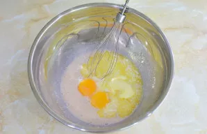 Tada įpilkite ištirpintą sviestą ir įmuškite kiaušinius. Išmaišykite.