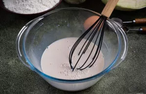 Supilkite šiltą pieną ir šluotele gerai išmaišykite, kol mieliai visiškai ištirps.