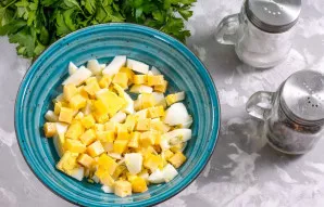 Bet kurios pasirinktos rūšies kietąjį sūrį supjaustykite vidutinio dydžio kubeliais ir sudėkite į indą prie kiaušinių.