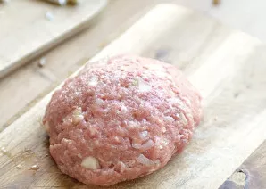 Iš faršo formuokite paplotėlius. Į kiekvieno vidų dėkite gabalėlį sūrio ir grybų įdarą. Suformuokite kotletus.