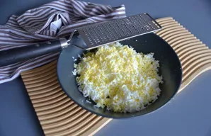 Tuo pačiu smulkumu sutarkuokite virtus kiaušinius ir sudėkite prie krabų lazdelių.