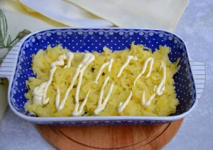 Įdėkite pusę bulvių į indo dugną ir patepkite majonezu.