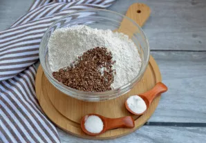 Sumaišykite du miltų tipus su linų sėmenimis, pridėkite sodą ir kepimo miltelius, gerai išmaišykite.