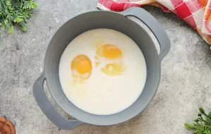 Į dubenį su pienu įmuškite kiaušinius ir išmaišykite iki vientisos masės.