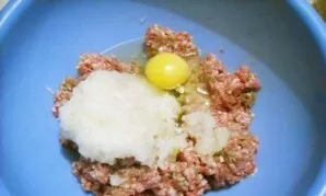 Paruoškite įdarą. Į maltą mėsą sudėkite smulkiai tarkuotą svogūną, druską, pipirus ir įmuškite kiaušinį. Gerai išmaišykite.