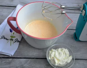 Į dubenį įdėkite grietinę ir įmaišykite ją mikseriu.