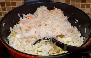 Prie svogūnų dedame šviežius kopūstus, troškiname apie 15 min. Tuomet dedame raugintus kopūstus ir troškiname toliau.