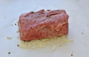 Svogūną nulupkite, supjaustykite pusžiedžiais ir sudėkite po mėsa.