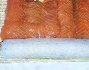 Apverskite nori lapą su ryžiais ir ant dumblių sudėkite papriką bei avokadą. Tuomet sluoksniais išdėliokite lašišą, kaip parodyta nuotrau...