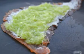 Ant sūrio uždėkite tarkuotą agurką ir tolygiai paskirstykite.