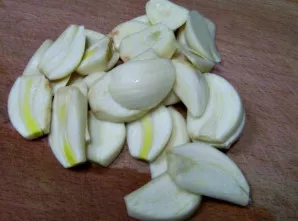 Nulupkite česnaką ir supjaustykite plonomis skiltelėmis arba mažais kubeliais. Dalį sudėkite ant kopūstų.