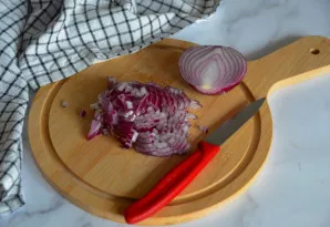 Smulkiai supjaustykite svogūną.