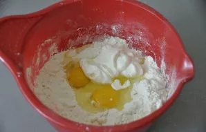 Įdėkite kiaušinius, grietinę ir užminkykite tešlą.