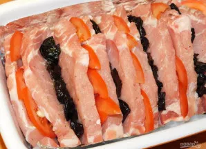 Tuomet į likusias įpjovas sudėkite džiovintas slyvas ir graikinius riešutus.