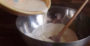 Po truputį, maišydami, supilkite gautą masę į miltus.