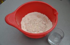 Supilkite į miltus ledinį vandenį, dalį vandens (apie penktadalį) pasilikite.