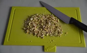 Smulkiai sukapokite pistacijas. Dalį jų naudokite pagrindui, o kitą dalį — dekorui.