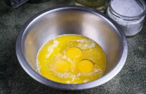 Į kitą dubenį įmuškite kiaušinius, įpilkite kondensuoto pieno ir ištirpinto sviesto.