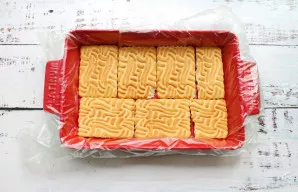 Formą išklokite plėvele ir išdėliokite cukrinius sausainius vienu sluoksniu.