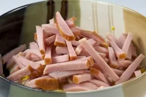 Supjaustykite kumpį juostelėmis.
