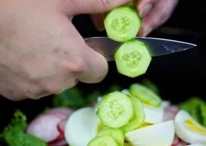 Nulupkite agurkus, supjaustykite plonais žiedais ir sudėkite į salotas.
