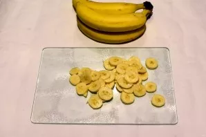 Bananą nulupkite ir supjaustykite plonais griežinėliais. Maždaug vienas vidutinis bananas dedamas ant vieno pyrago sluoksnio.