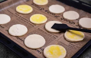 Sudėkite visus apskritimus ant kepimo skardos, išklotos kepimo popieriumi, ir patepkite plakto vištos trynio bei 2 a. šaukštelių vandens ...