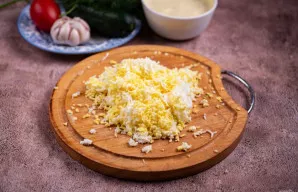 Išvirtus kiaušinius atvėsinkite, nulupkite ir sutarkuokite smulkia tarka.