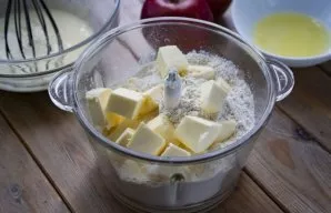 Į didelį trintuvo dubenį sudėkite atšaldyto margarino arba sviesto kubelius ir suberkite miltus.