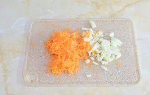 Tuo tarpu paruoškite daržoves. Nulupkite svogūną ir morką. Svogūną smulkiai supjaustykite, morką – sutarkuokite.