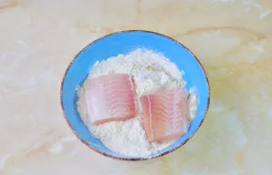 Kiekvieną žuvies gabalėlį gerai apvoliokite miltų mišinyje iš visų pusių.