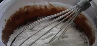 Į būsimą tešlą persijokite miltus su kepimo milteliais. Dar kartą viską išmaišykite.