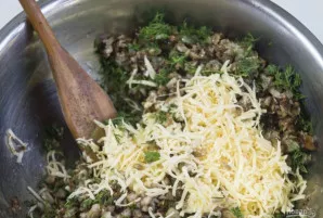 Į paruoštą įdarą įdėkite sūrį ir smulkiai pjaustytus žalumynus. Dabar galite įdaryti grybus.