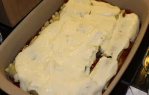 Užpilkite „Bešamelio“ padažu ir paskirstykite visame paviršiuje. Jei norite, kanelonus galima paruošti ir be „Bešamelio“.