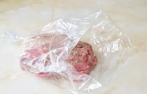 Mėsą iš visų pusių aptepkite augaliniu aliejumi ir sudėkite į kepimo maišelį.
