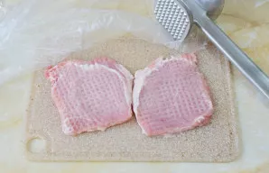 Kiekvieną mėsos gabalėlį uždenkite plėvele ir atsargiai plakite virtuviniu plaktuku.