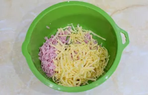 Tuo metu paruoškite įdarą. Sutarkuokite kumpį ir sūrį.