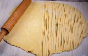 Tešlą iškočiokite ant darbastalio į ploną lakštą ir supjaustykite plona juostele (kaip makaronams).