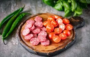 Per tą laiką supjaustykite salami plonais griežinėliais, o visus vyšninius pomidorus perpjaukite į dvi dalis.