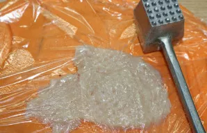 Vištienos krūtinėlę uždenkite maistine plėvele ir lengvai pamuškite.