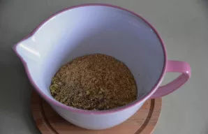 Į dubenį sudėkite sutrintus sausainius ir dalį pistacijų.