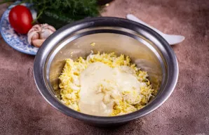 Į didelį dubenį sudėkite tarkuotus kiaušinius, įdėkite majonezą, per česnakų spaustuvę išspauskite česnako skilteles.