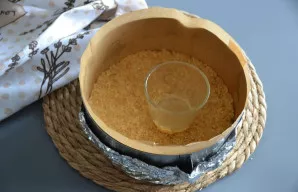 Sausainių masę sudėkite į formą ir gerai suspauskite stikline. Įkaitinkite orkaitę iki 200 °C ir kepkite pagrindą 10 minučių.