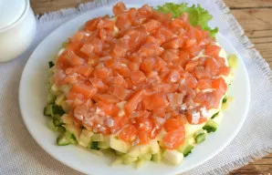 Lašišą supjaustykite mažais kubeliais ir dėkite ant obuolių sluoksnio.