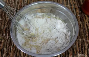 Dalimis pilkite šiltą pieną ir gerai išmaišykite tešlą šluotele.