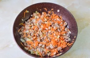 Į keptuvę su kalakutiena sudėkite smulkintą svogūną ir morką. Išmaišykite. Kepkite dar 2–3 minutes.